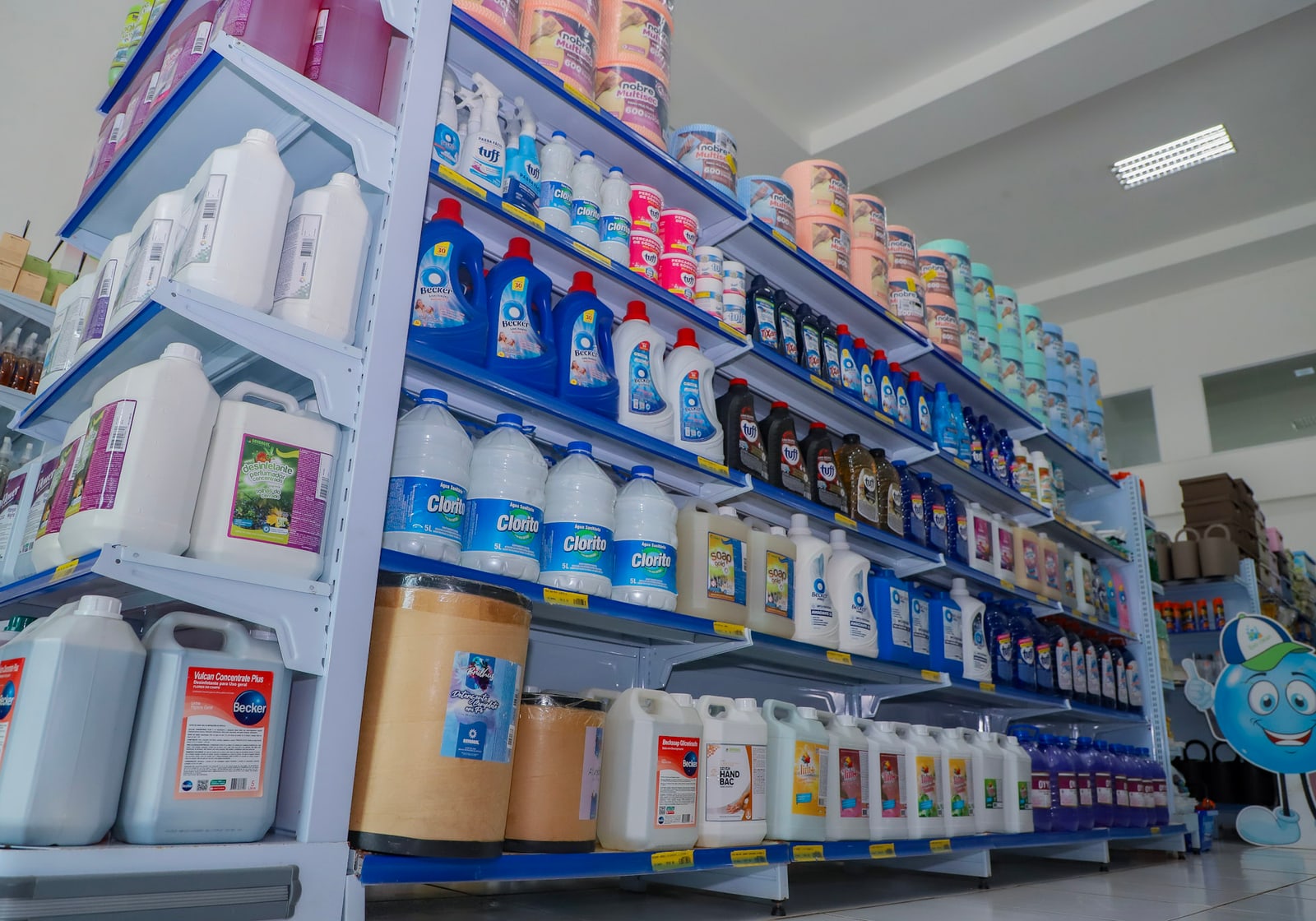 Corredor da loja Evo Clean com prateleiras de saneantes, lava-roupas e descartáveis